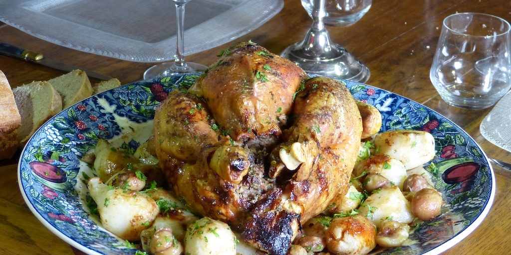 Photo de la dinde farcie aux marronx posée sur un lit de châtaignes et de topinambours dorés au four.