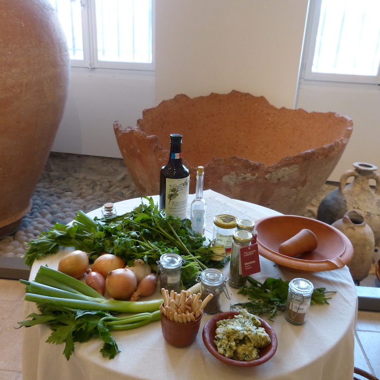 Valence-musée-les-causeries-culinaires-recette-fait-maison-boutique-saveur-histoire Photo de la table avec des produits de consommation de l'époque romaine, en arrière plan des amphores et des délia d'époque.