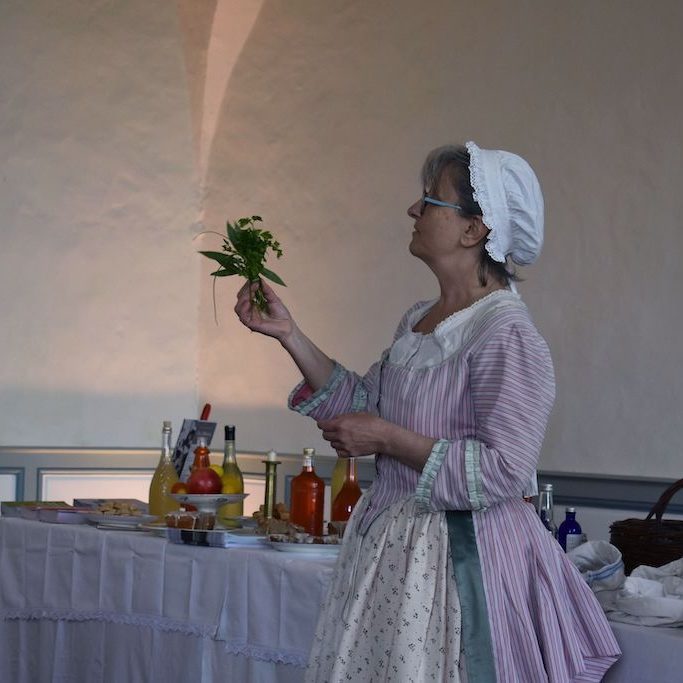 Atelier-18e-abbaye-Belleperche-les-causeries-culinaires-recettes-ancetres-boutique-cours-cuisine-histoire L'animatrice en costume montrant le bouquet garni du XVIIIe siècle.