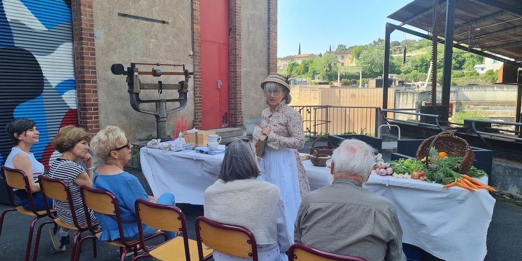 Atelier-19e-saut-du-tarn-les-causeries-culinaires-recettes-ancetres-boutique-cours-cuisine-histoire Photo de l'animatrice costumée présentant les livres de cuisine du XIXe siècle.